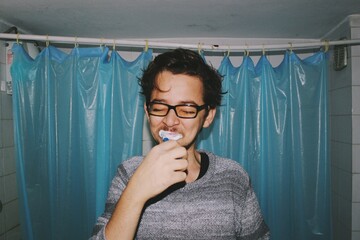 portrait of a person brushing teeth in bathroom