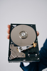 Obraz premium hard drive disassembled in a man's hand on a gray background
