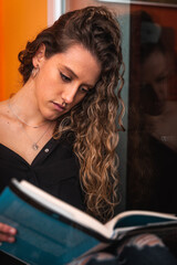 Young woman reading a book next to the window