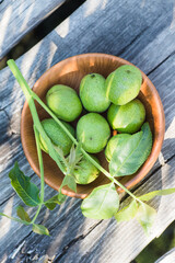 Smoothy unripe green walnuts on an old vintage table. Leaves on branch of nut. Collect ingredients for tincture of nuts.
