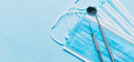 Two dental instruments sitting on some blue surgical masks on a blue background