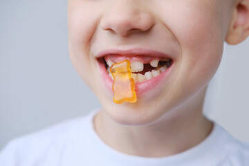 boy, kid holds in his mouth and eats gelatinous sweets, gummy bear, concept of children's delicacy,...