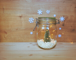 View of a jar filled with white capsules and a Christmas tree with lights and Christmas ornaments on wooden background with copy space. Medical or pharmacology background.