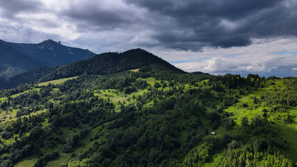 Green hills with scattered trees at the base of Mount Ceahlau - Romania with Toaca Peak in background