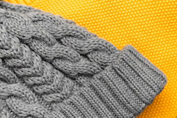 Close up of knitted yellow sweater and gray hat on it in trendy colors. Colors of the 2021 year. Cozy knitted clothing, warm concept