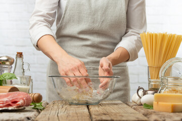 Professional chef mix ingredients with hands in glass bowl for cooking pasta alla carbonara. Backstage of preparing traditional italian dish on white background. Frozen motion. Cookbook illustration.