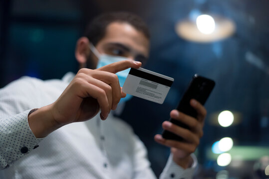 Black african man holding hands credit card and mobile phone, online paying during corona pandemic.Technology, internet banking, e-commerce healtcare  and online concept