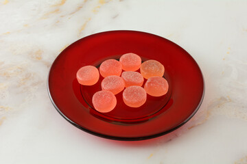 Sweet watermelon gummy candy pieces on small red dessert plate on table