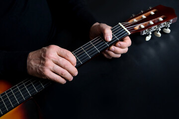 Fototapeta na wymiar guitarist tunes instrument, man plays the guitar, close-up hands, the concept of creativity, learning to play musical instruments, online learning