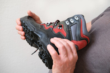 man holds in his hands red, black work boots strauss, concept of highest product quality, special...