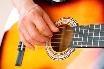 Fototapeta premium man plays the guitar, close-up hands, the concept of creativity, learning to play musical instruments, online learning