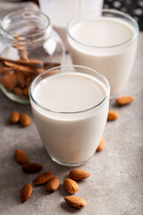 Homemade organic almond milk in a glass on stone background with cinnamon sticks.