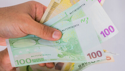 Abstract and conceptual of Banknotes in hand and money, in euros, close up on white background. Business and financial concept, isolated on white mirror desk.