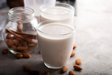Homemade organic almond milk in a glass on stone background with cinnamon sticks.