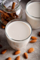 Homemade organic almond milk in a glass on stone background with cinnamon sticks.
