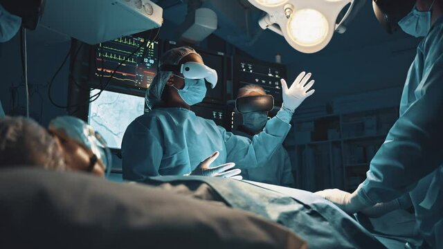 Surgeons team surrounding patient on operation table. Medical workers wearing virtual reality glasses looking brain and heart infographic high tech at operation room before the surgical intervention