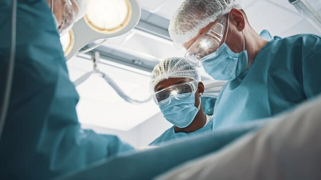 Low angle of the concentrated surgeon man with his assistants making blepharoplasty, plastic surgery operation for correcting disfigurations of eyelids and for aesthetically modifying the eye region