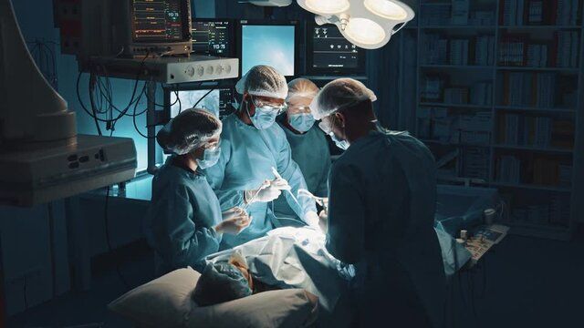 Operation in surgery. High angle view of the qualified doctors and nurse control patients health with help of modern techniques, while making a modern hard operation. Advanced medicine concept