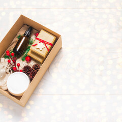 Present box with eco organic cosmetics, holiday decorations and lights on white wooden background. Zero waste Christmas concept. Flat lay copy space