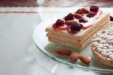 Closeup of gluten-free diet rice toasts with strawberry jam, raisins and almonds on glass pate. Concept of healthy food. Copy space.