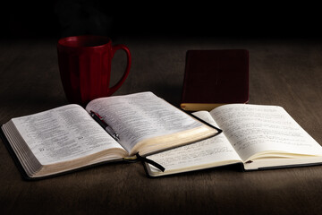 Open bible and notebook with book of prayer and red mug