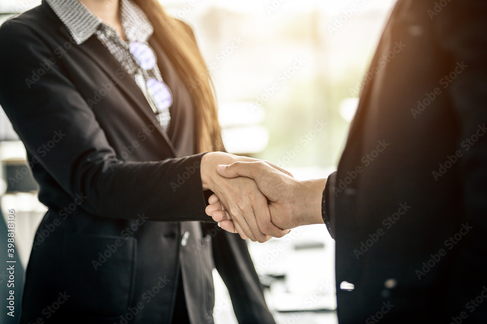 Wall mural businesswoman and businessman shaking hands at in the office room background after the contract is s