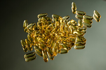 Fish oil capsules with omega 3 and vitamin D on a mirror background, shiny texture, healthy...