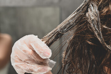 A young woman puts a healing mask on her hair at home. The girl coloring her hair in her own...
