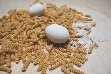 Bucati fusilli raw pasta, eggs, and flour. Handmade Italian macaroni. Natural food, farm products concept.