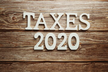 Taxes 2020 alphabet letter on wooden background