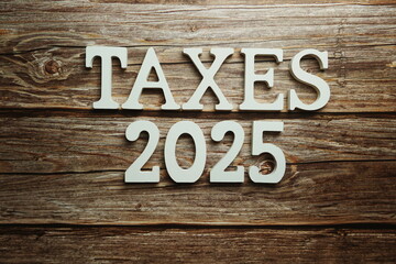 Taxes 2025 alphabet letter on wooden background