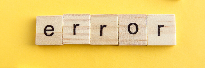 On the wooden blocks written ERROR, wooden blocks on a yellow background, top view, flat ley