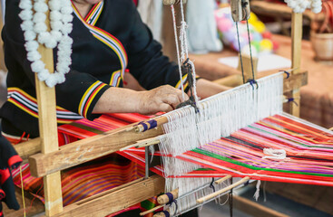 Closeup and crop hands of Thailander Hill tribe ladies are demonstration of weaving colorful fabric for tourists in her village.