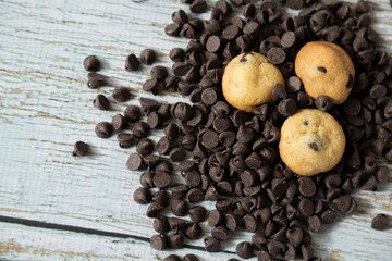 Mini chocolate chip cookies on chocolate chips on a white wooden background - gourmet snacks - fine pastries