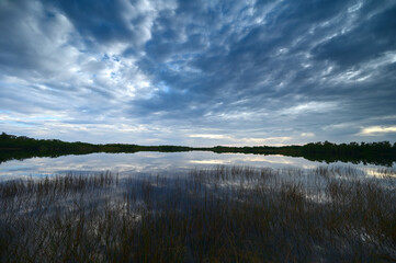 Sunrise cloudscape reflected on tranquil water of Nine Mile Pond in Everglades National Park, Florida.
