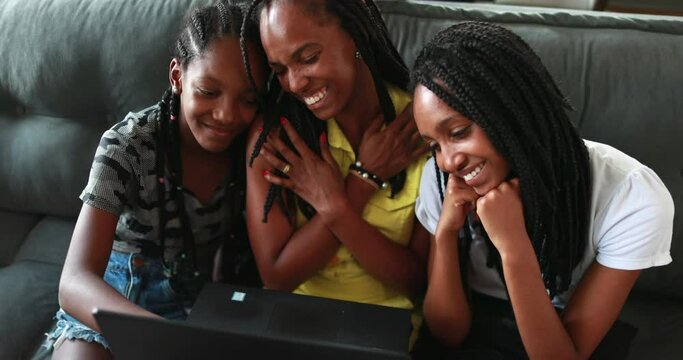 Family speaking on webcam. African mom and teen daughters at home sofa sending heart symbols