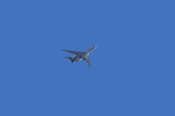 Passenger jet airplane with the landing gear out approaching an airport under blue sky