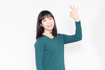 白背景の前に立ってOKのジェスチャーをする女性