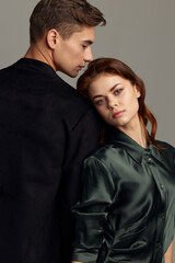 Enamored man and woman stand with their backs to each other front view gray background