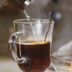 Pour hot water into a glass mug with instant coffee from the kettle.