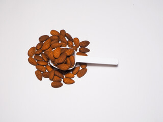 Almonds on a plastic spoon on a white background