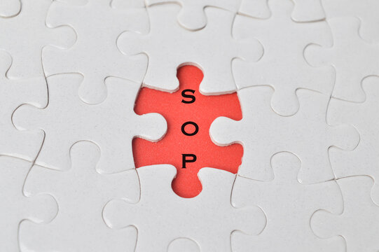 Top view of jigsaw puzzle with word SOP stands for Standard Operating Prosedure. Business and education concept.
