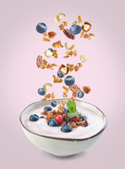 Bowl with tasty yogurt, granola, nuts and berries on color background