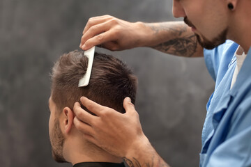 Professional hairdresser working with client in barbershop