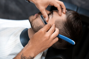 Obraz na płótnie Canvas Hairdresser shaving client in barbershop