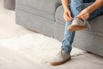 Young man putting on stylish shoes