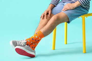 Young man in stylish shoes and orange socks on color background