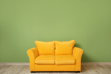 Stylish sofa near color wall in room