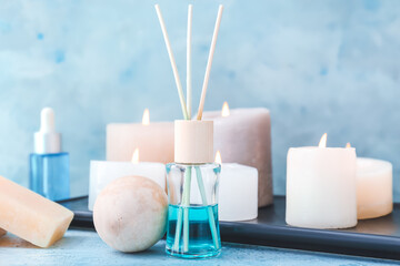 Reed air freshener and candles on color background