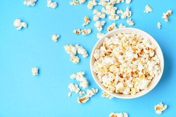Bowl of tasty popcorn on color background